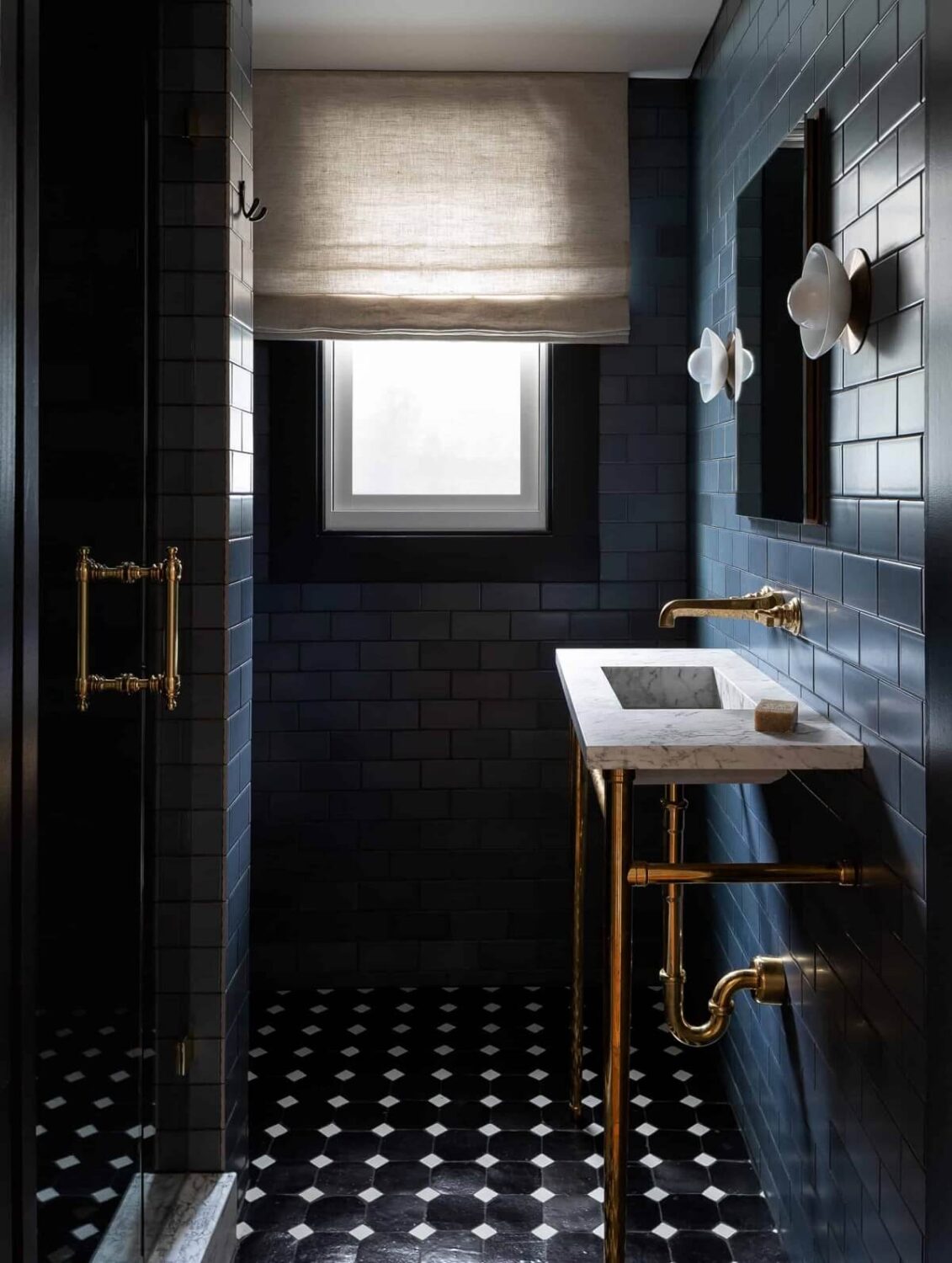 small moody bathroom with dark blue tiles and marble sink nordroom